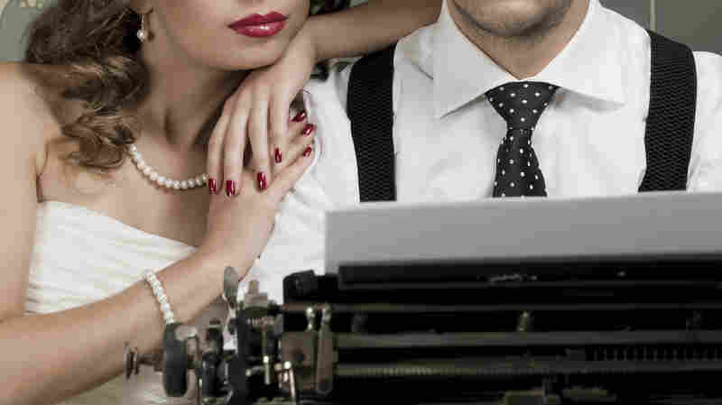 A man and a woman at a typewriter.