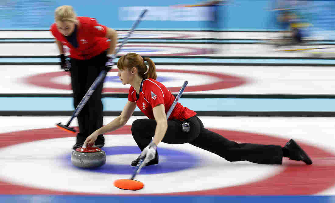 Britain's Claire Hamilton delivers the rock while her teammate Anna Sloan prepares to sweep during the women's curling semifinal game against Canada during the Sochi Winter Olympics on Wednesday. Canada won 6-4.
