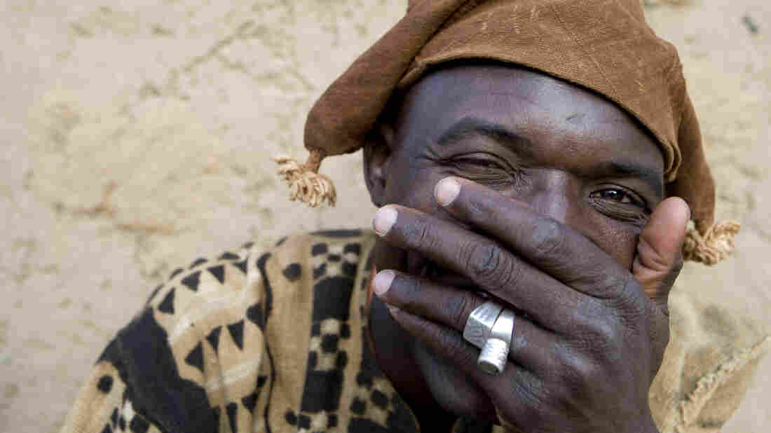 A man covers his mouth as he laughs.