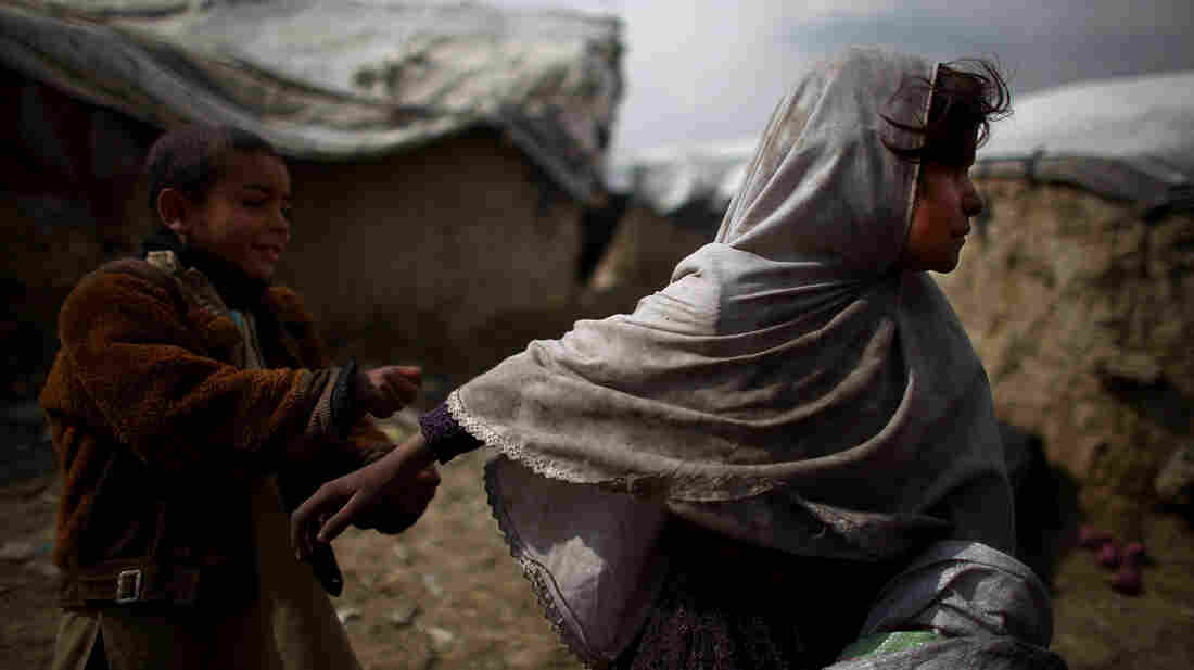 A little girl runs away from her brother while playing outside of the family's home in the Nasaji Bagrami camp for internally displaced Afghans in Kabul.