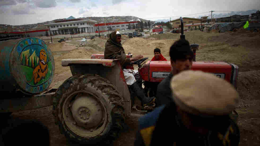 Rosadin, who lives nearby, tows a small water tank into the camp with his tractor. He fills dirty plastic jugs. Residents pay about 50 cents for about 5 gallons of water.