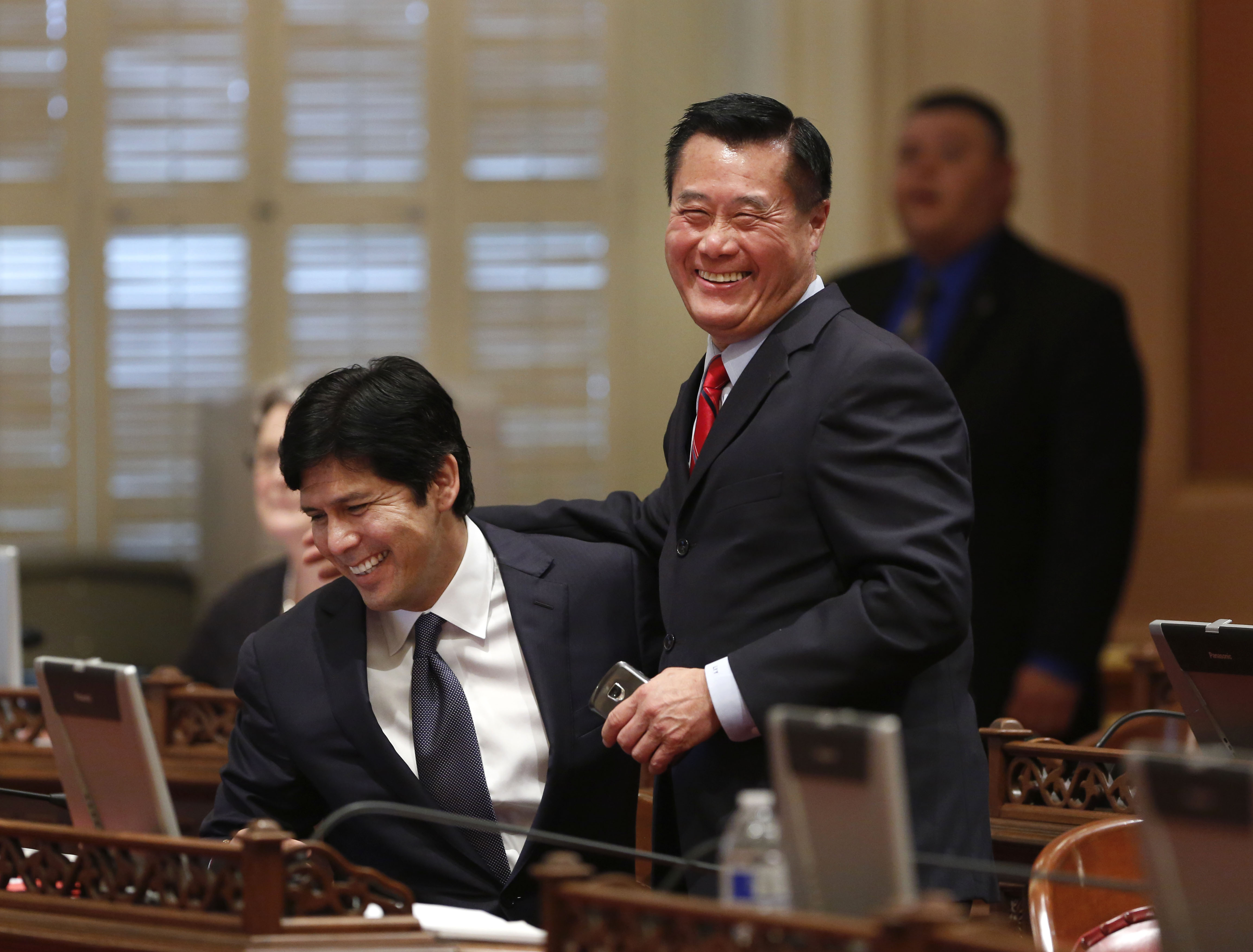 Senador estatal Leland Yee, D-San Francisco, a la derecha, y Sen. Kevin de Leon, demócrata de Los Ángeles, celebra la aprobación de sus medidas de control de armas durante la sesión del Senado en el Capitolio en Sacramento, California, en 2013. (Rich Pedroncelli/AP)