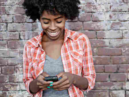 Black woman text messaging on cell phone