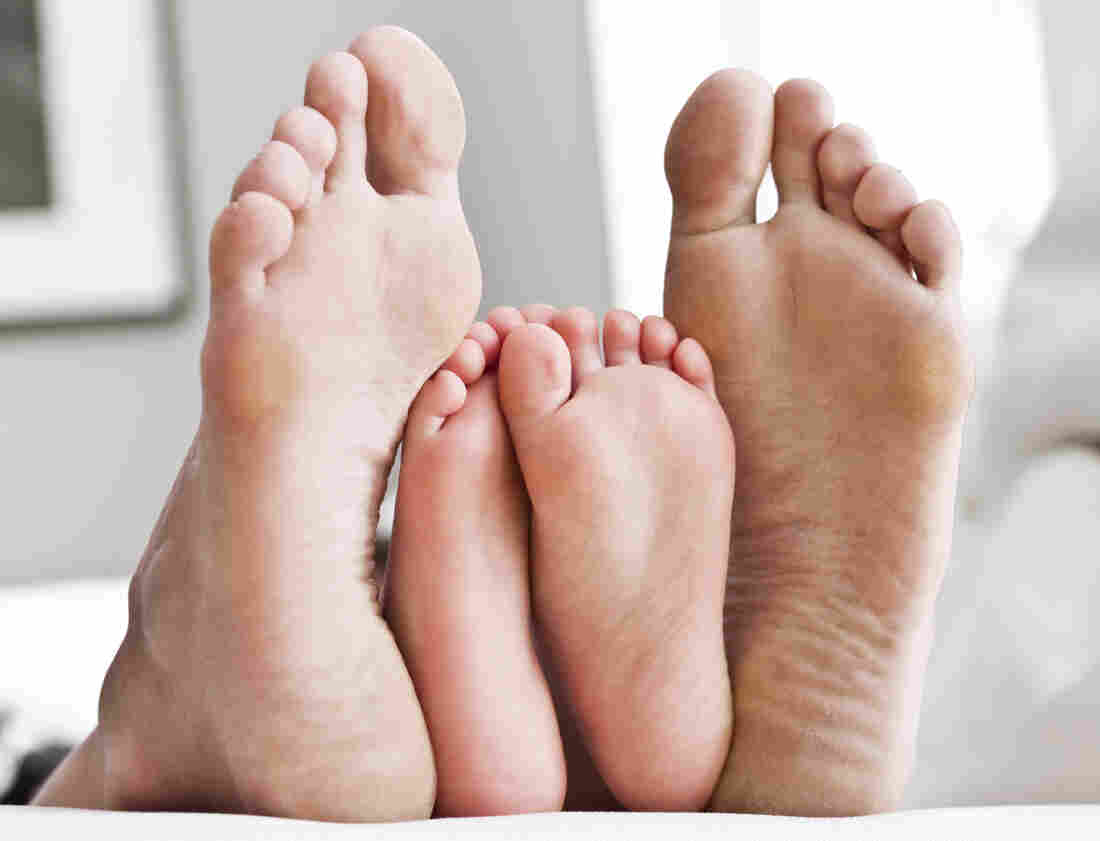 A pair of adult feet framing the feet of a child.