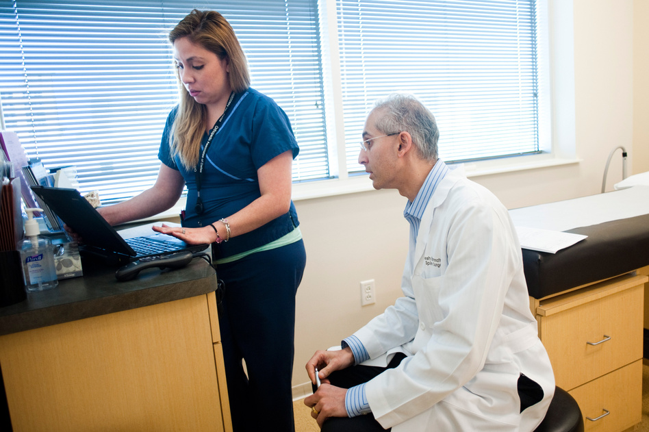 Medical scribe Connie Gayton keeps the electronic records, allowing orthopedic surgeon Devesh Ramnath to focus on his patients. (Brandon Thibodeaux for NPR)