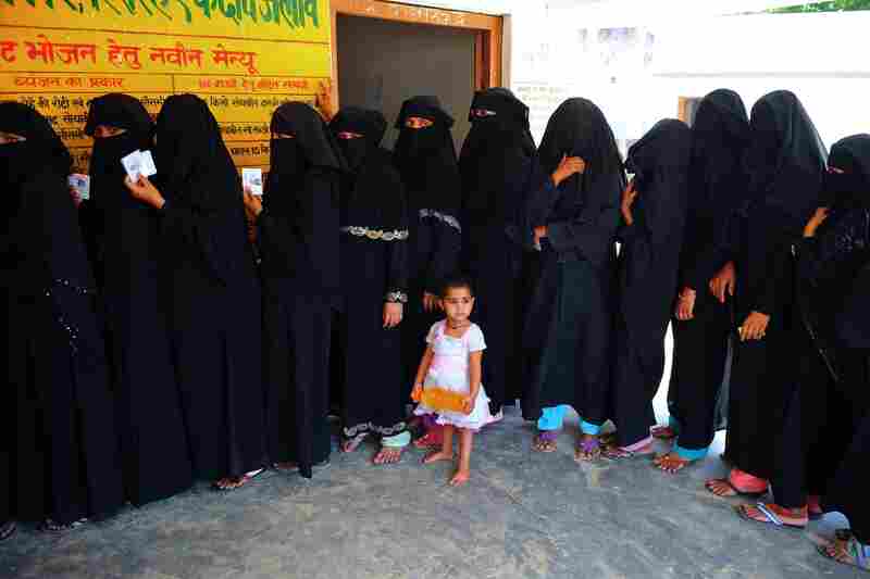 A child looks on as Muslim women wait in line to cast their votes at a polling station in Azamgarh, India on May 12.