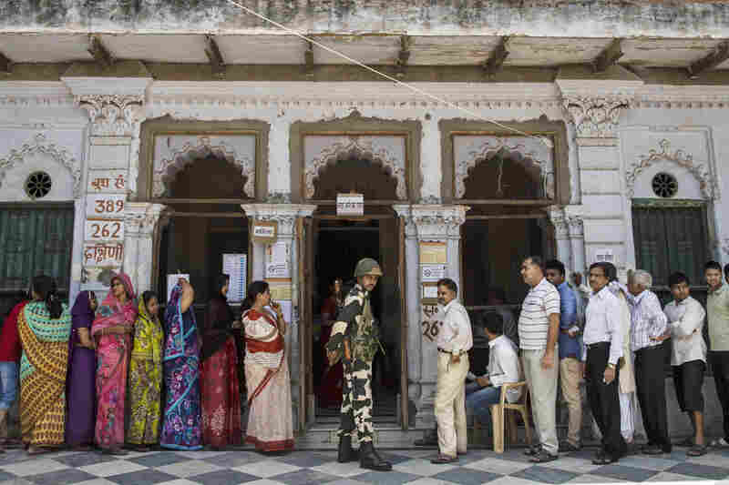 A Border Security Force officer stands guard as Indian citizens wait in line to vote at a polling station on May 12.
