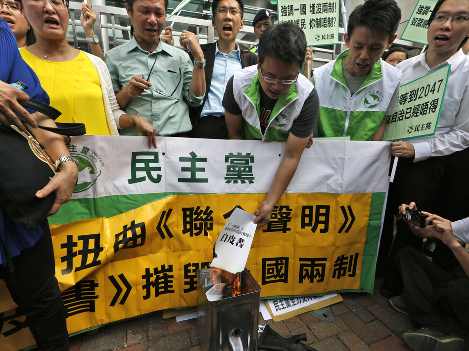 Protesters burn a mock "white paper" released by China's State Council on Tuesday, which says Beijing holds ultimate control over the former British colony. (Kin Cheung/AP)