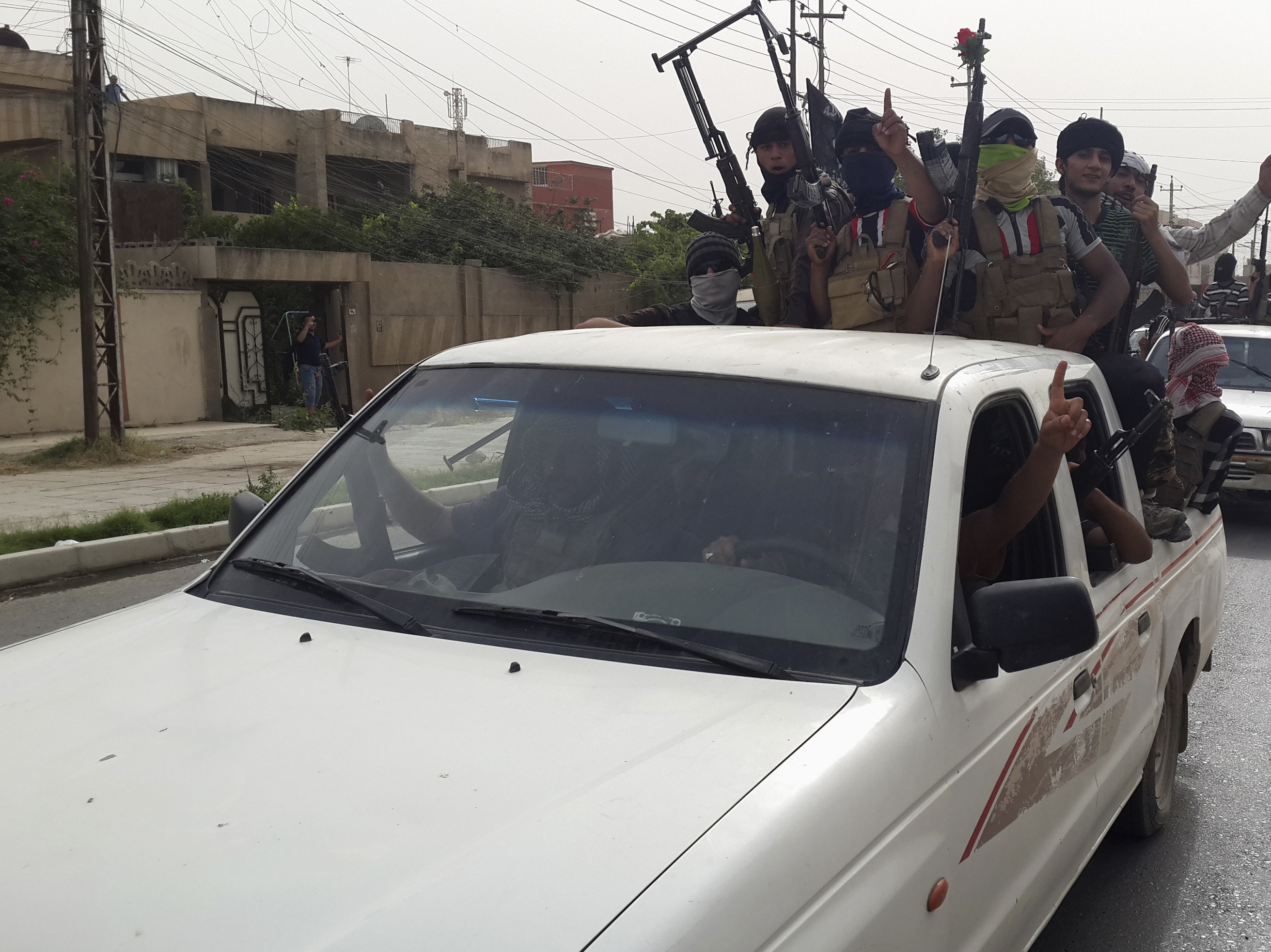 Fighters of the Islamic State of Iraq and Syria celebrate on vehicles taken from Iraqi security forces in Mosul, Iraq, on Thursday.