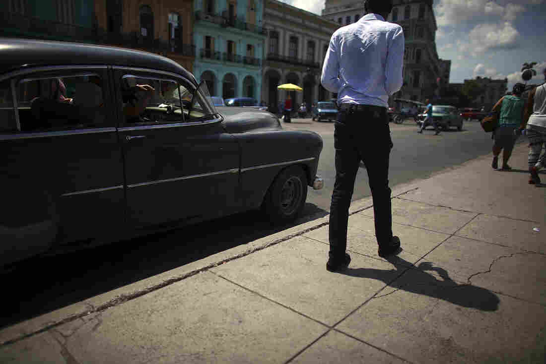 17: Man walking next to black car.
