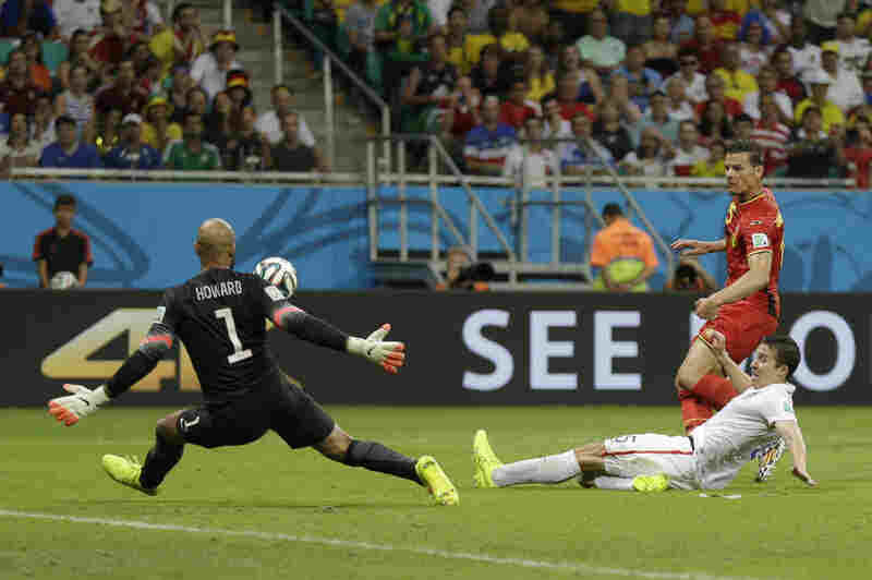 United States' Matt Besler tries to defend as Belgium's Daniel Van Buyten takes a shot on goalkeeper Tim Howard.