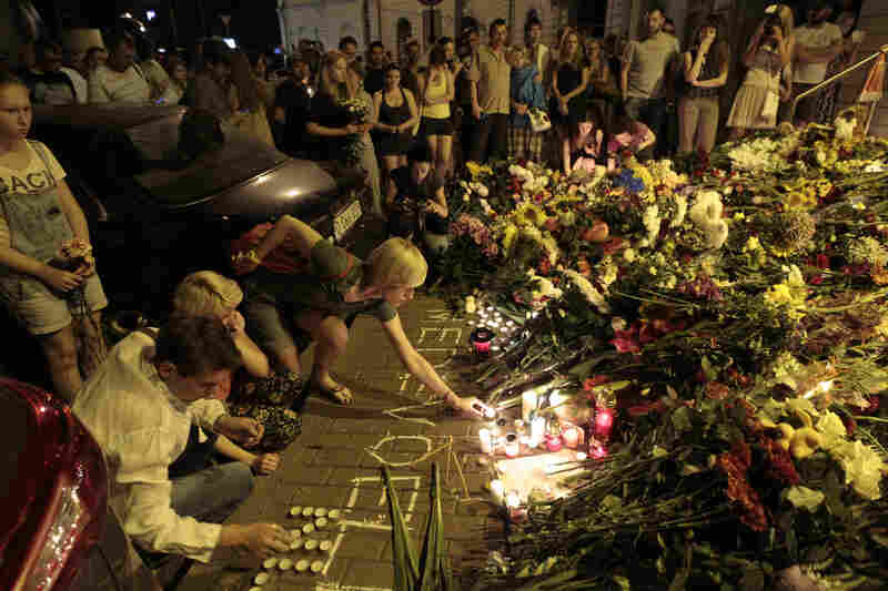 People hold candles and place flower tributes outside the Dutch Embassy in Kiev to commemorate victims of the crash.