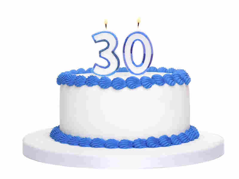Birthday cake decorated with blue frosting and number thirty candles.