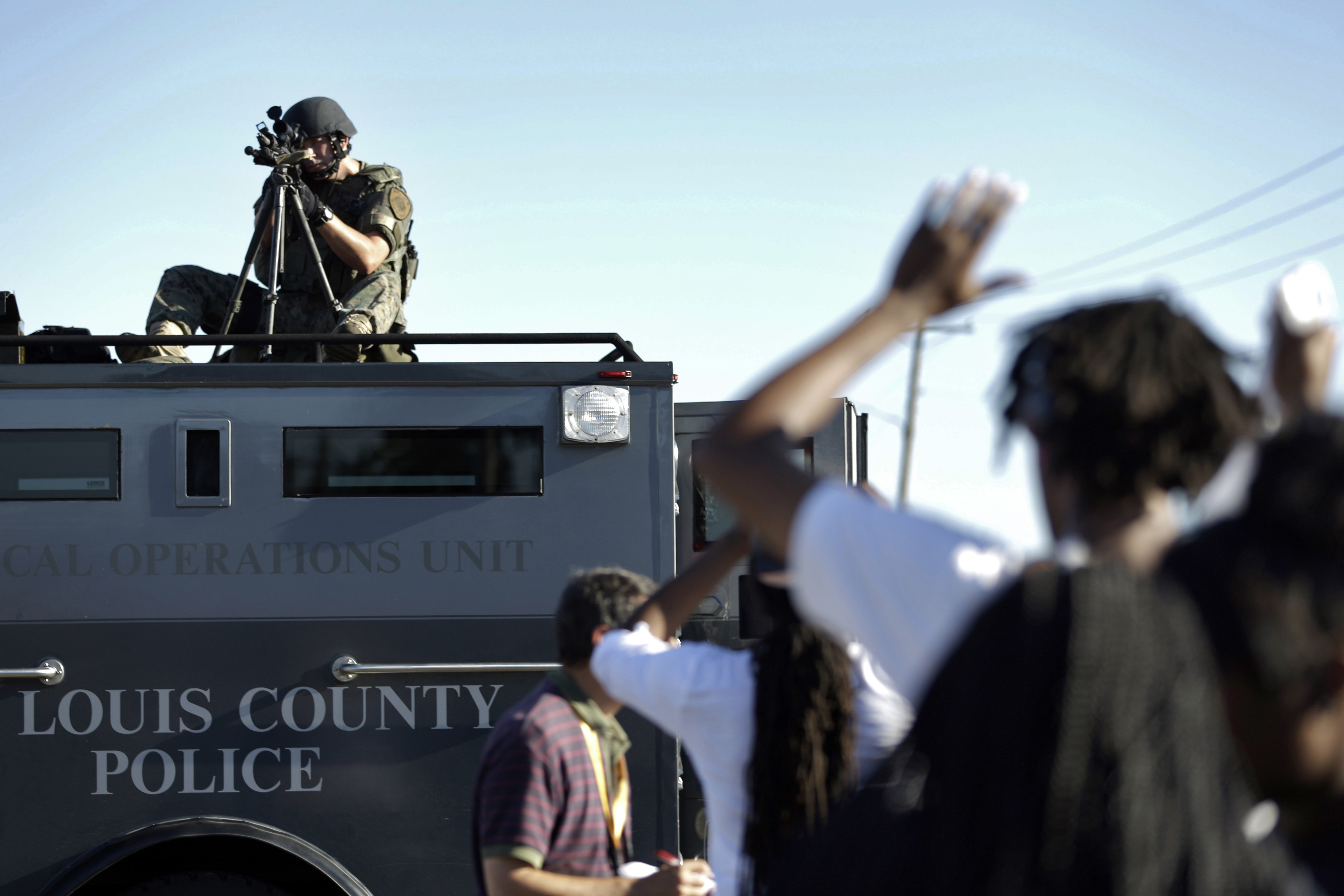 A member of the St. Louis County Police Department points his weapon in the direction of a group of protesters in Ferguson.