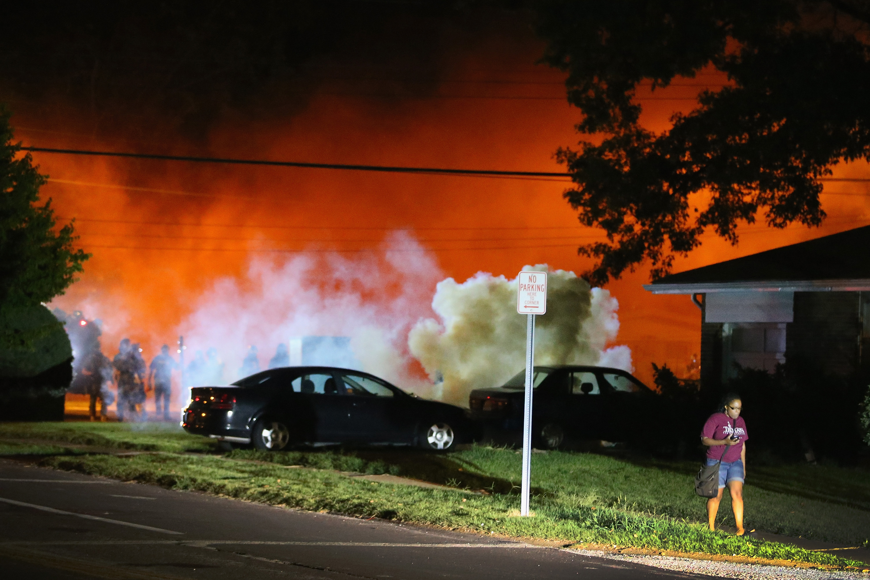 A young woman walks from a corner after police standing near the corner fired tear gas at her Wednesday.