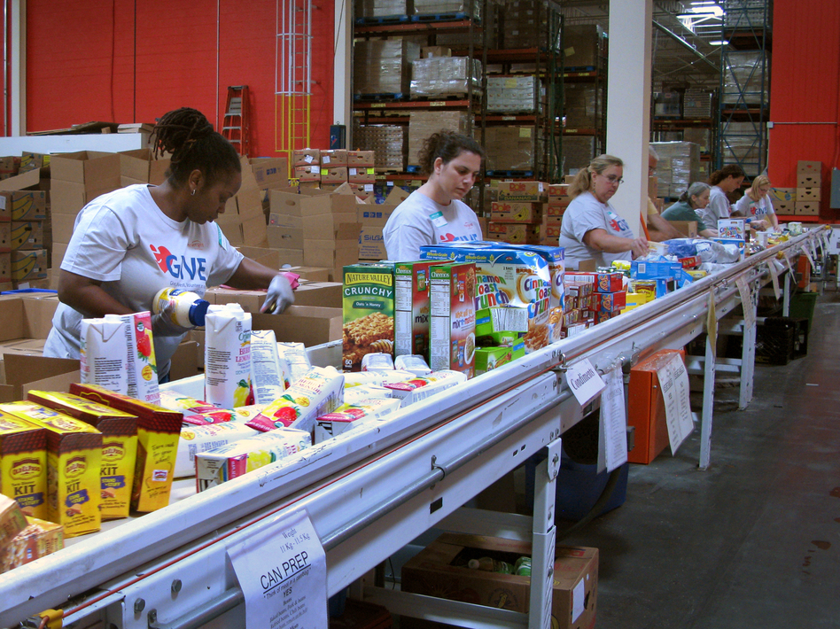 Volunteers at the Maryland Food Bank in Baltimore sort and box food donations on a conveyor belt. The bank started working with groups like the USO in 2013 to provide food aid to families affiliated with nearby military bases. (Pam Fessler/NPR)