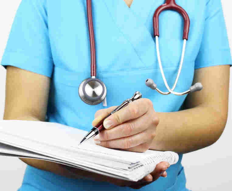 A nurse writes notes on a pad of paper.