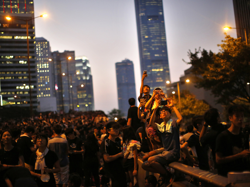 Protesters take pictures with their mobile phones on Monday as they block the main street to the financial Central district, outside the government headquarters in Hong Kong. (Carlos Barria/Reuters/Landov)