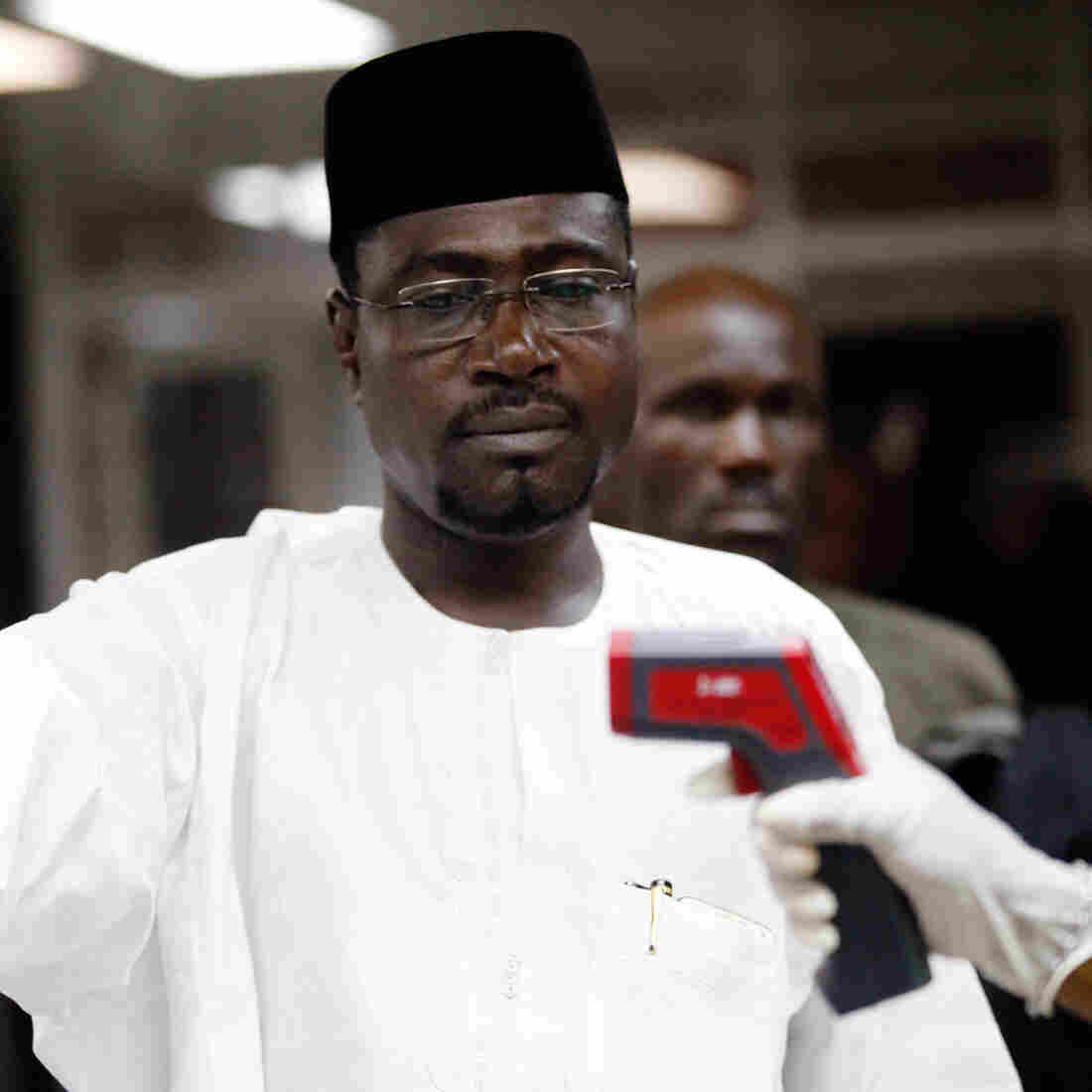 A health official uses a handheld infrared thermometer on a passenger arriving at Murtala Muhammed International Airport in Nigeria.