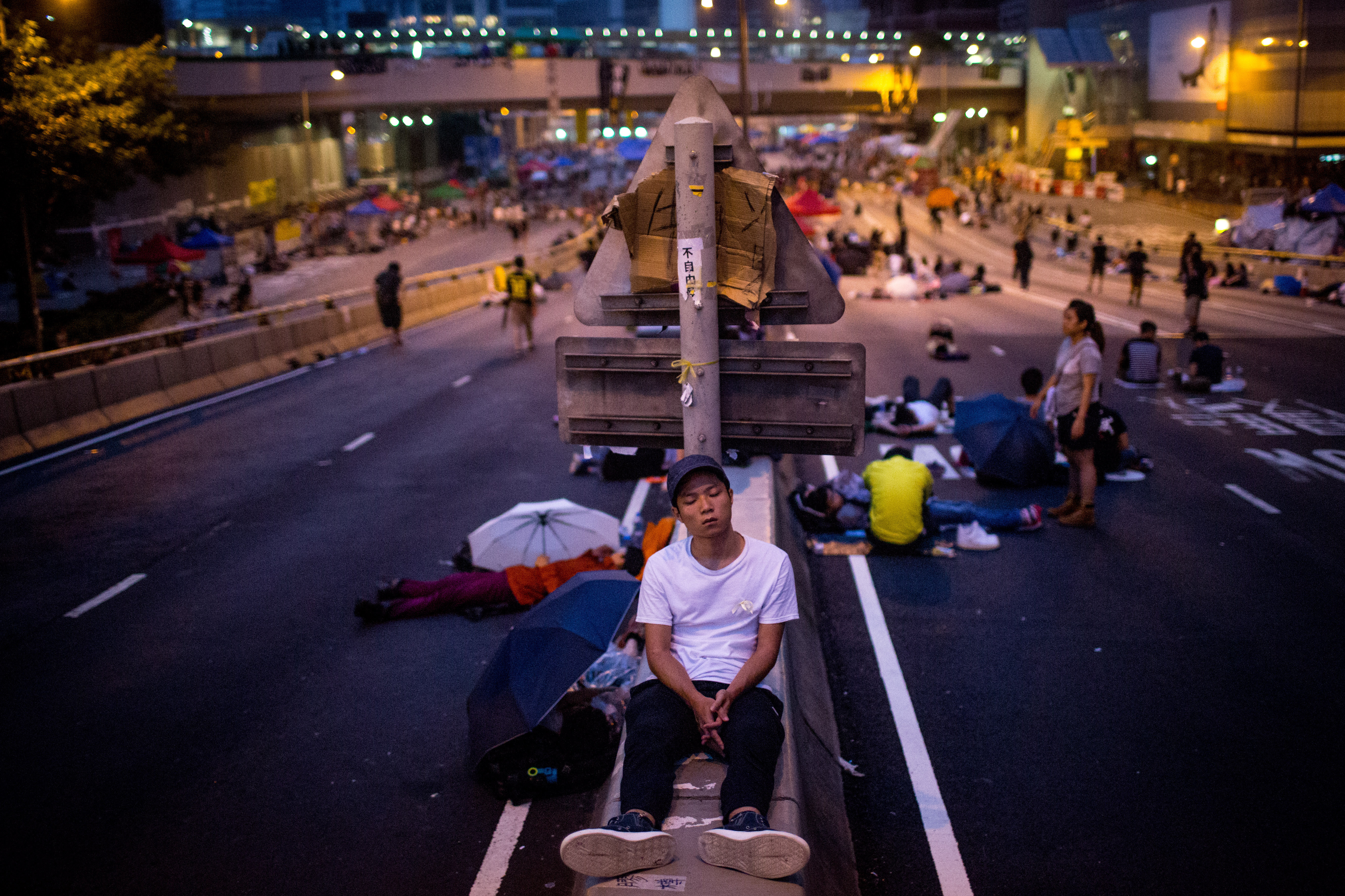 A pro-democracy protester sleeps on a concrete road divider on a street outside the Hong Kong Government Complex on Sunday in Hong Kong.