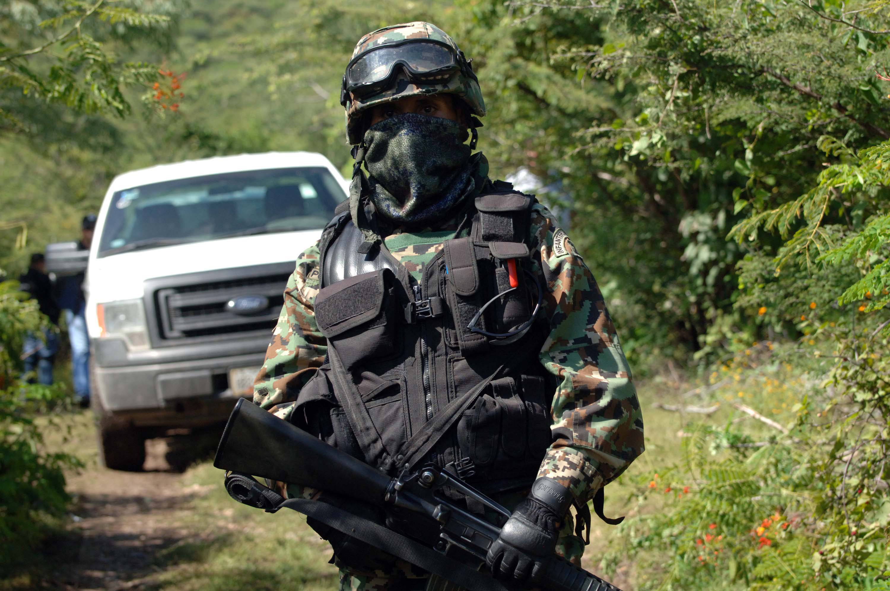 A Mexican navy marine guards the road that leads to the site where an alleged clandestine mass graves were found near the city of Iguala, Mexico.