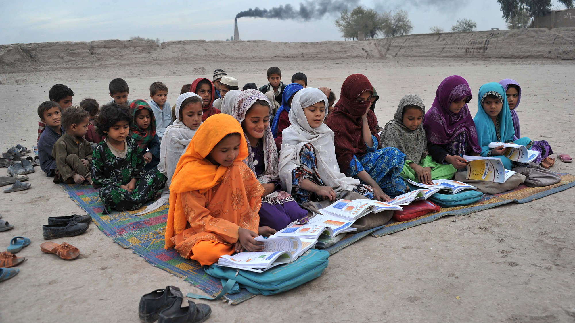 Afghan schoolgirls take lessons outdoors at a refugee camp near Jalalabad.