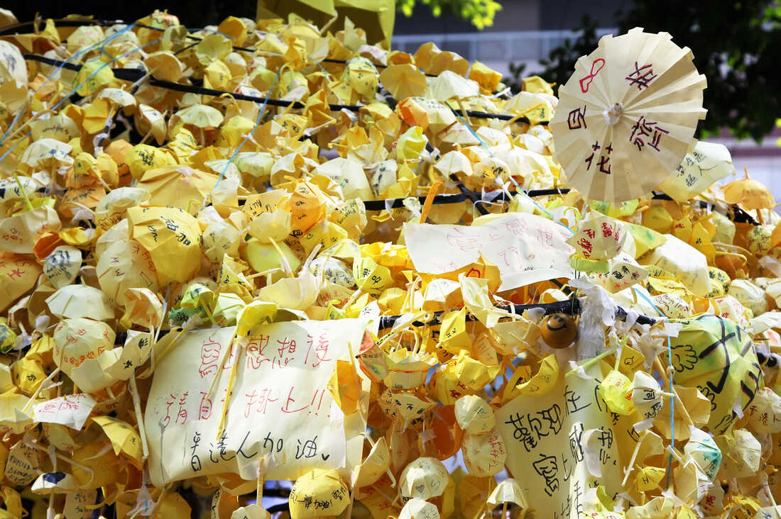 A yellow umbrella made of tiny yellow umbrellas with messages of hope written in Chinese.