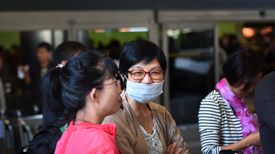 A passenger wearing a face mask arrives at Los Angeles International Airport Friday. Federal officials now require people traveling from West Africa to enter the U.S. at one of five airports equipped to screen them for signs of Ebola. (Mark Ralston /AFP/Getty Images)