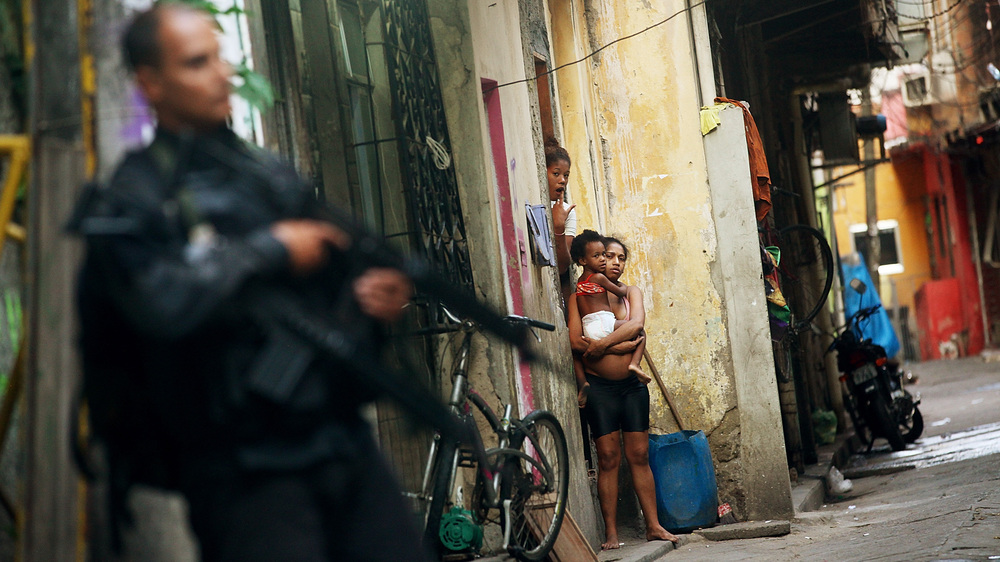 Residents look on as Brazilian military police officers patrol Mare, one of the largest complexes of favelas in Rio de Janeiro, Brazil, on March 30. In one of the world's most violent countries, homicide rates are dropping — but only for whites. (Getty Images)