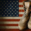 Grunge U.S. Army boots on sandy american flag background collage