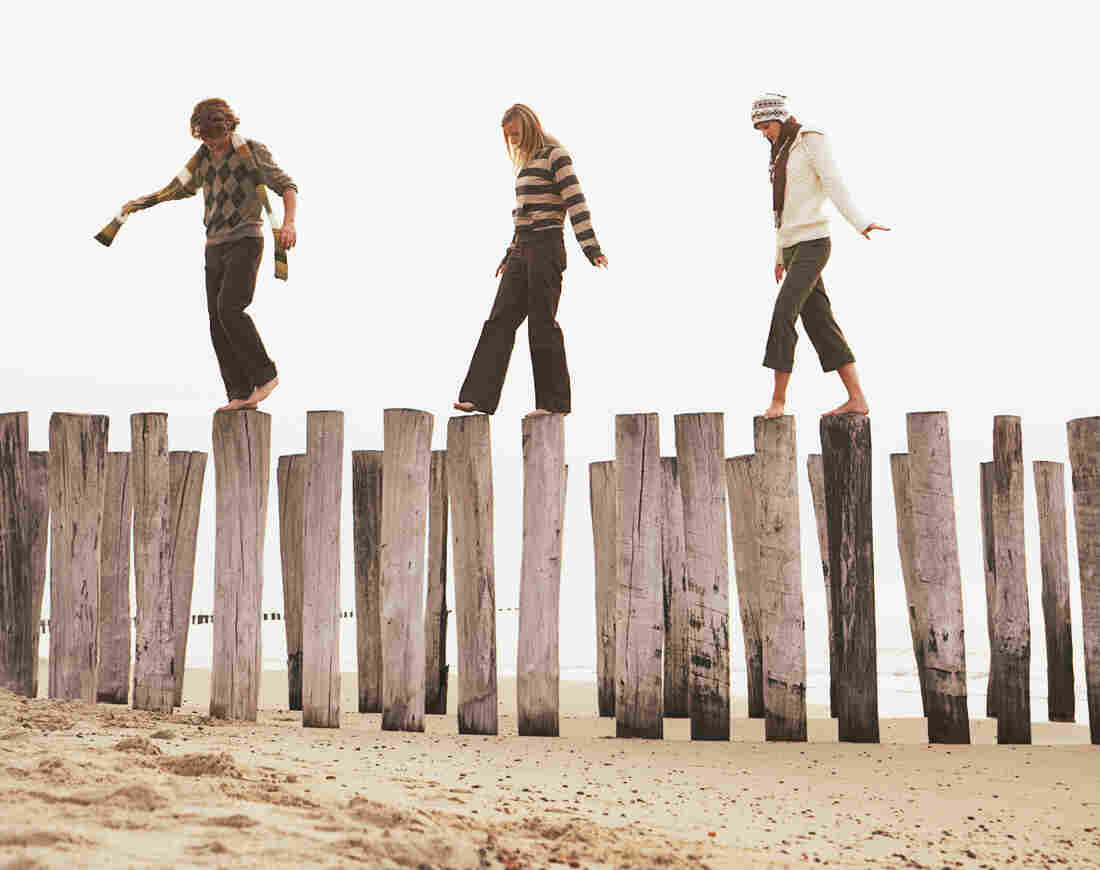 Friends balance on pilings at the beach.