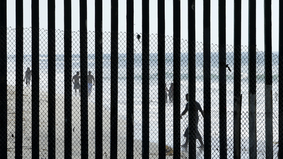 People walk along the beach in Tijuana, Mexico, near San Diego, where metal bars marking the border with the U.S. meet the sea. (Gregory Bull/AP)
