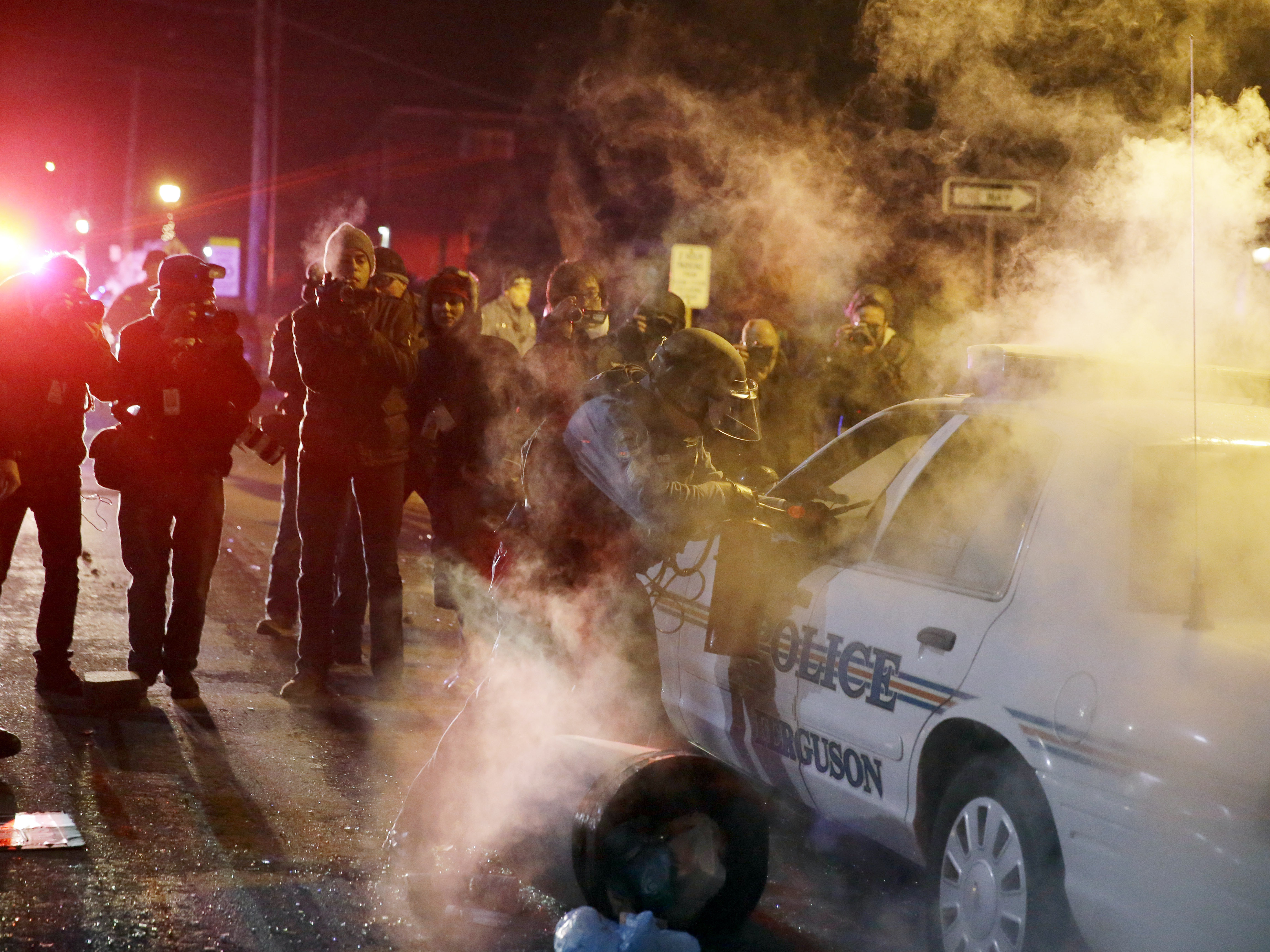 A police officer approach a police vehicle Tuesday night in Ferguson, Mo., after a protester threw an incendiary device onto it.