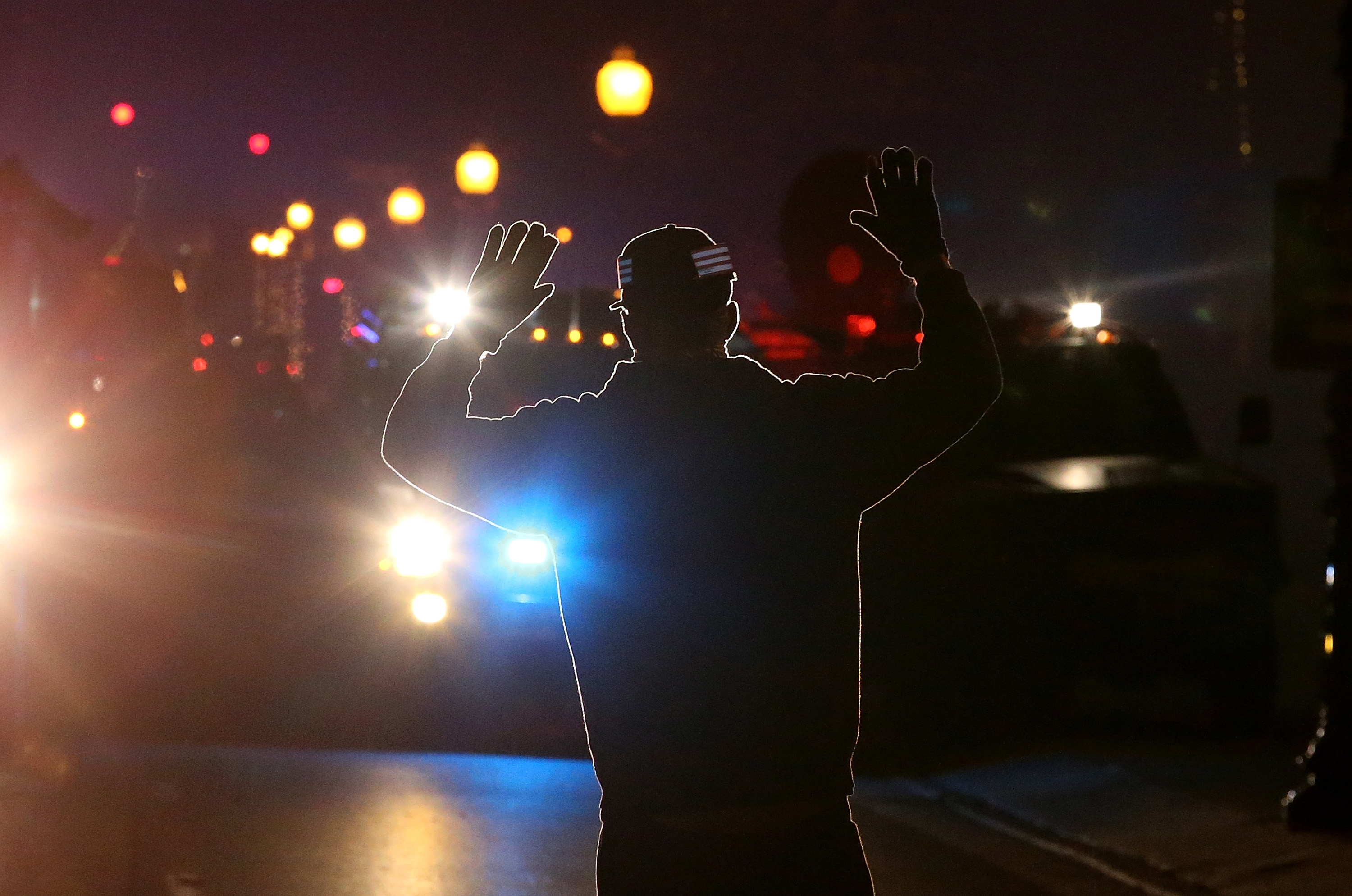 A protester stands in front of police vehicles with his hands up during a demonstration in Ferguson. More than 80 people were arrested in the St. Louis area.