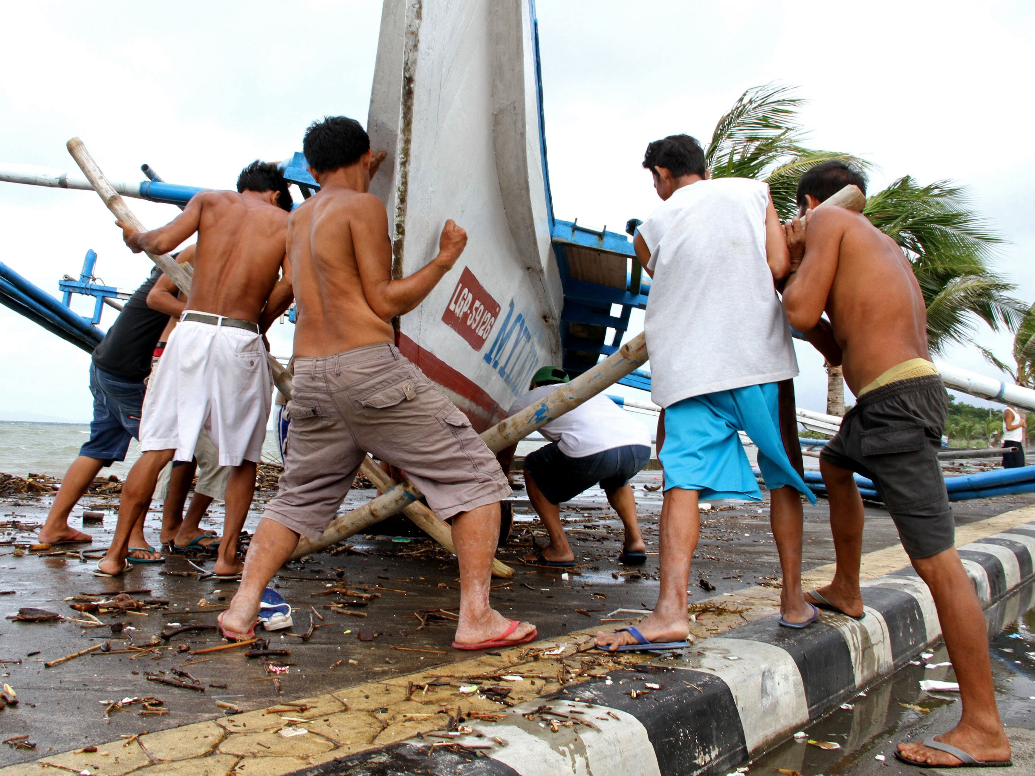 Fishermen carry their outrigger to higher ground Friday in Legazpi City, south of Manila.