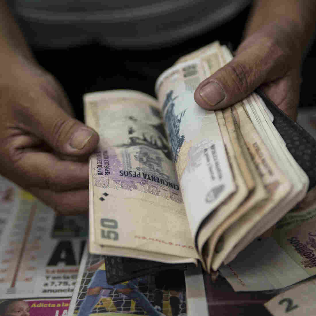 A newsstand owner counts Argentine pesos in Buenos Aires. Many Argentines carry large amounts of cash, saying they do not trust banks. This has contributed to a surge in robberies. A newsstand owner counts Argentine pesos in Buenos Aires. Many Argentines carry large amounts of cash, saying they do not trust banks. This has contributed to a surge in robberies.