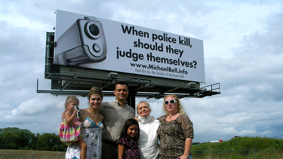 Michael Bell Sr. (center) and his family stand near one of the billboards they bought in a campaign to bring awareness to internal police investigations. Bell's son was shot and killed by police in Kenosha, Wis. (Courtesy of the Bell family)