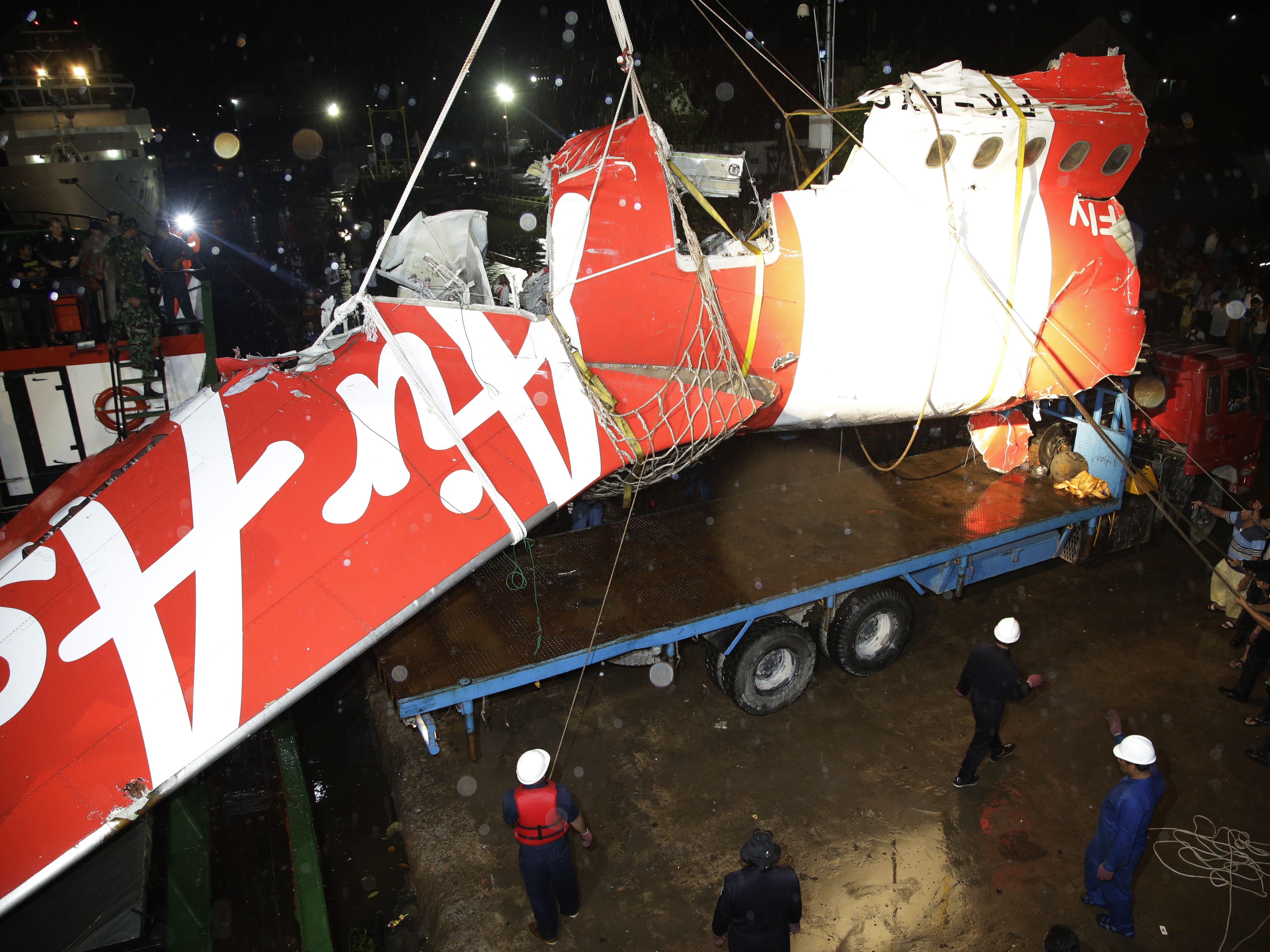 Crew members of Crest Onyx ship and Members of National Search And Rescue Agency unload the wreckage of part of the ill-fated AirAsia Flight 8501 on Sunday.