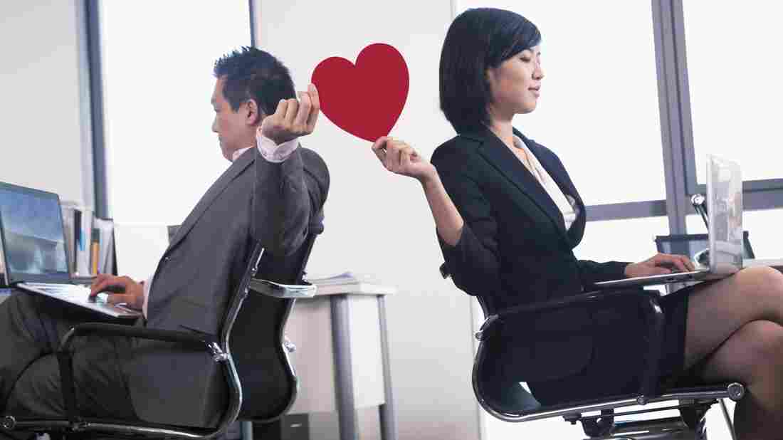 Work romance between two business people holding a heart.