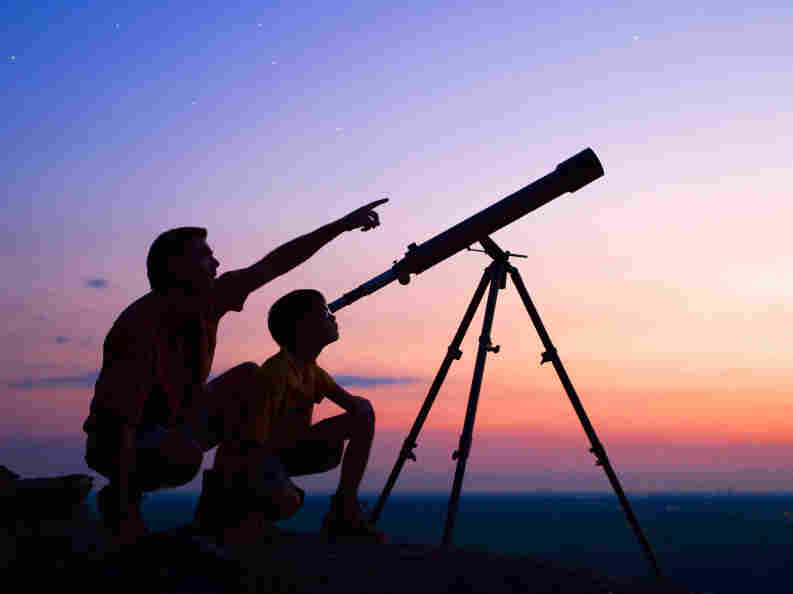 A boy and his dad look through a telescope.