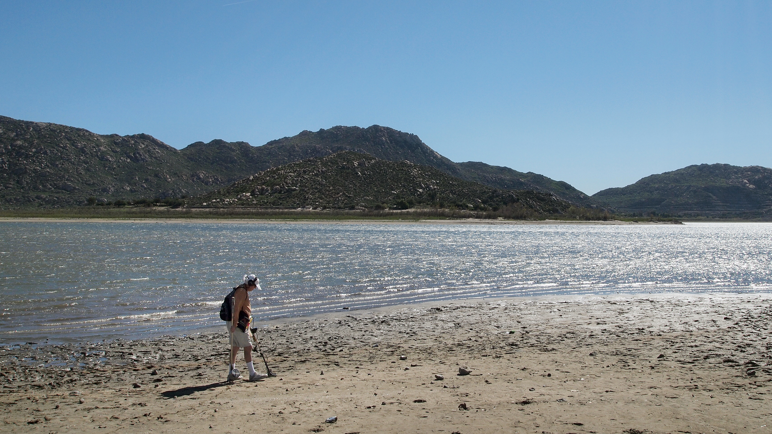 Marty Gabriel, a retired truck driver, passes his metal detector over the exposed sand at California's Lake Perris. Gabriel has been visiting the lake for 25 years. &quot;We definitely need rain,&quot; he says. (NPR)