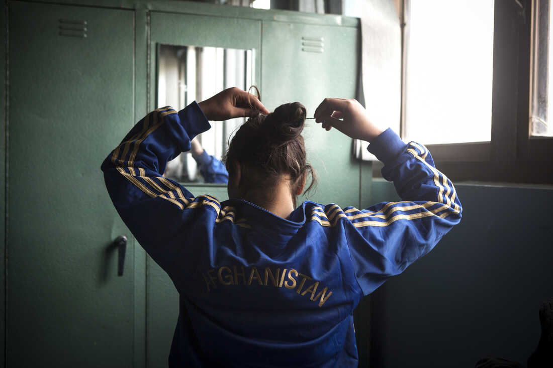 At the Spartan gym with no bathroom or showers, a girl puts up her hair before practice.