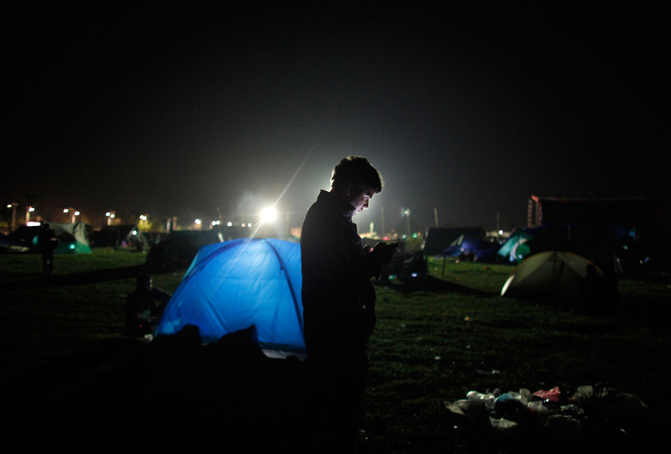 A Nepalese man checks his cellphone as people stay on open ground from fears of earthquake tremors in Kathmandu, Nepal, on Monday. (Niranjan Shrestha/AP)