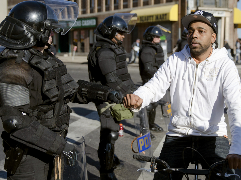 A man on a bicycle greets Maryland state troopers on Tuesday in the aftermath of rioting in Baltimore. (Matt Rourke/AP)