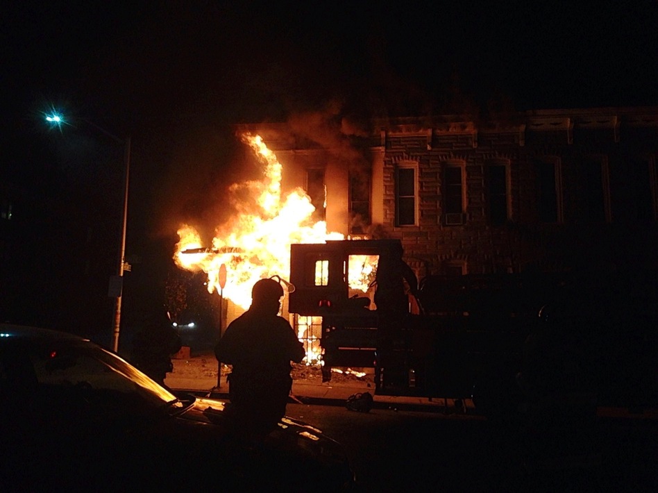 A police officer watches a corner market burn in the west side of Baltimore.
