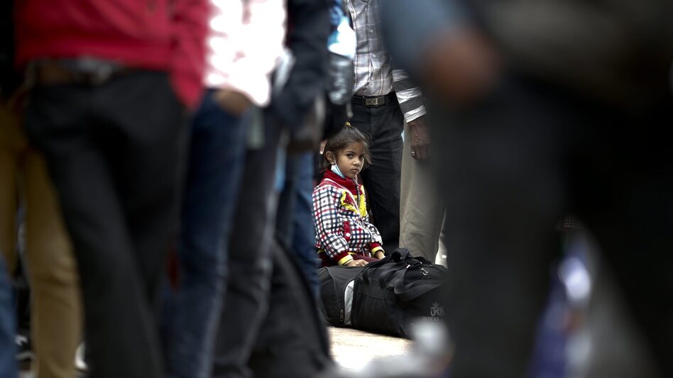A young girl sits on her luggage as she waits in a long line with her family, hoping to board buses provided by the government to return to their homes outside Kathmandu. (Diego Azubel/EPA /LANDOV)