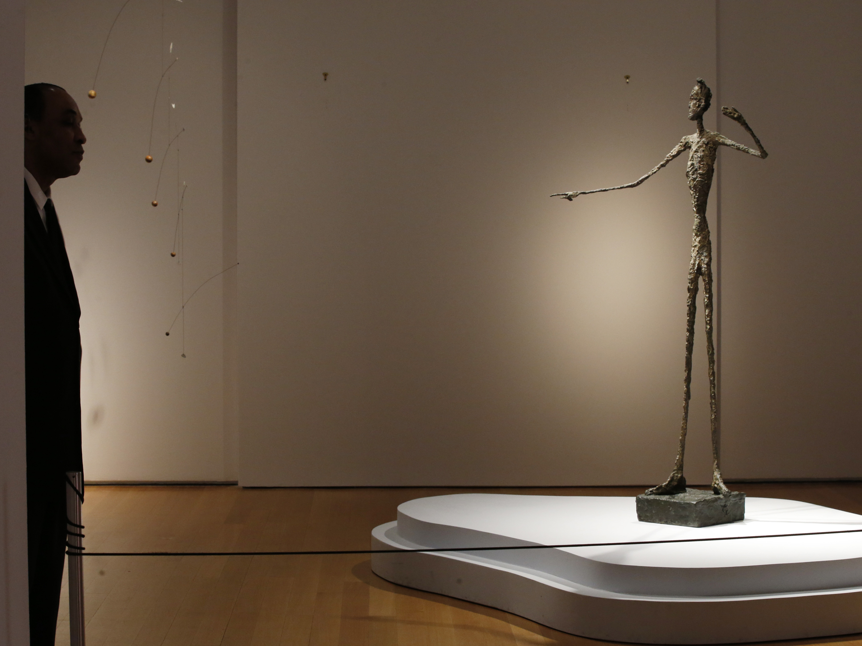 A guard stands beside Alberto Giacometti's life-size bronze sculpture Pointing Man after it sold for more than $141 million Monday, earning it the title of most expensive sculpture sold at auction — a title it took from another Giacometti sculpture sold for more than $100 million in 2010.