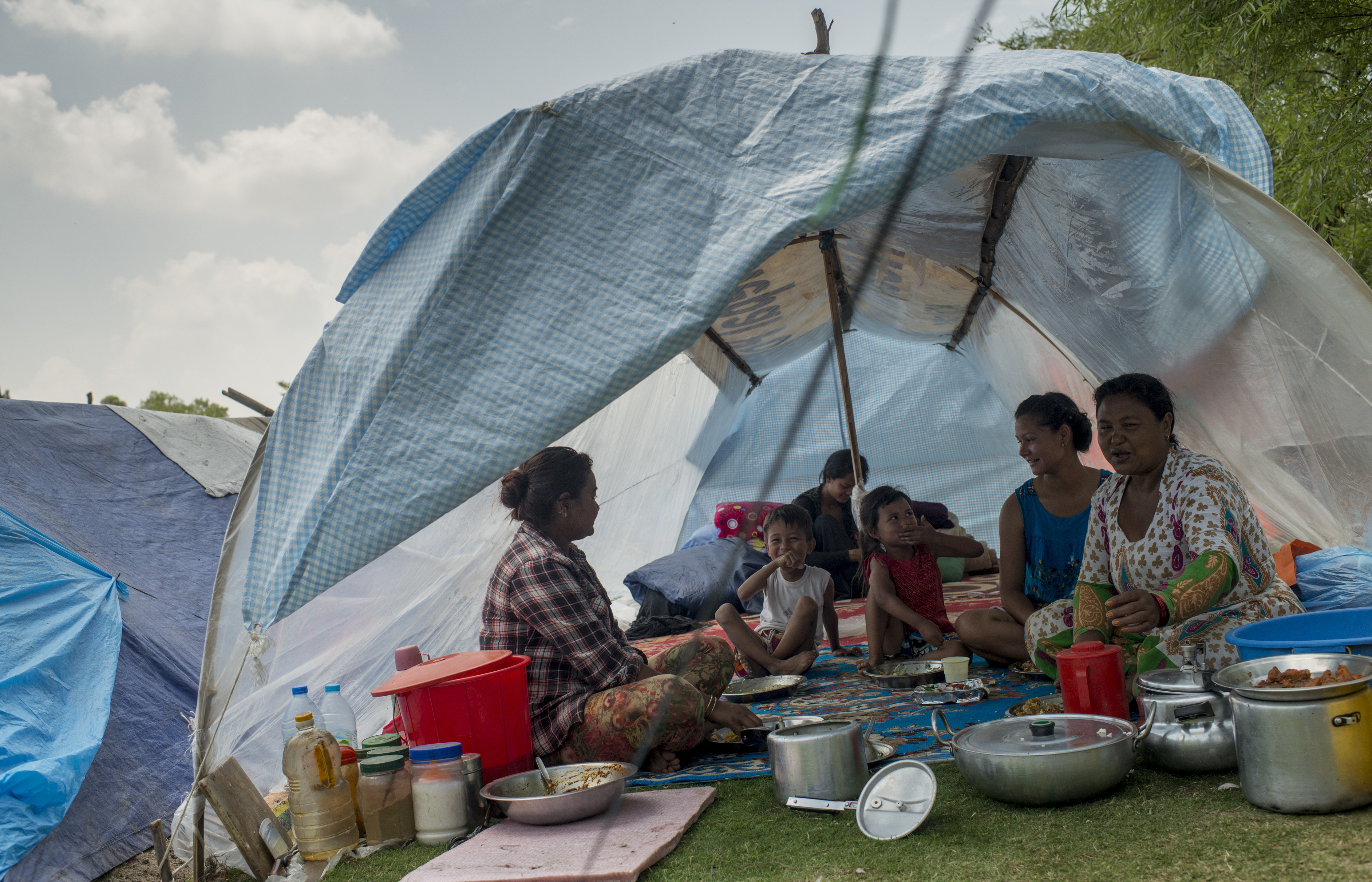 A family sits inside a tent at Kathmandu's golf course Wednesday, a day after a strong earthquake hit the area.