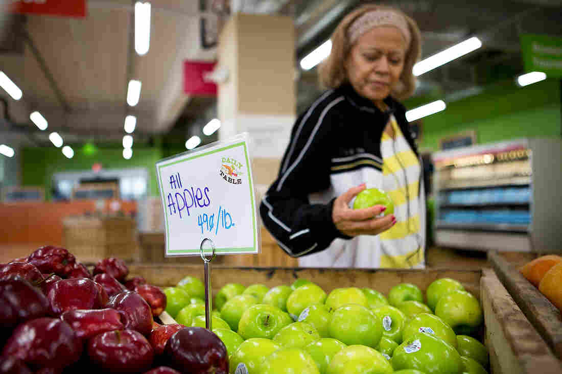 Noemi Sosa looks at an apple as she shops at Daily Table, the first nonprofit supermarket. It's located in Dorchester, Mass.