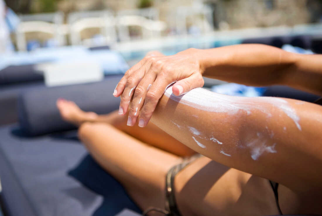 A woman applies sunscreen at the pool.